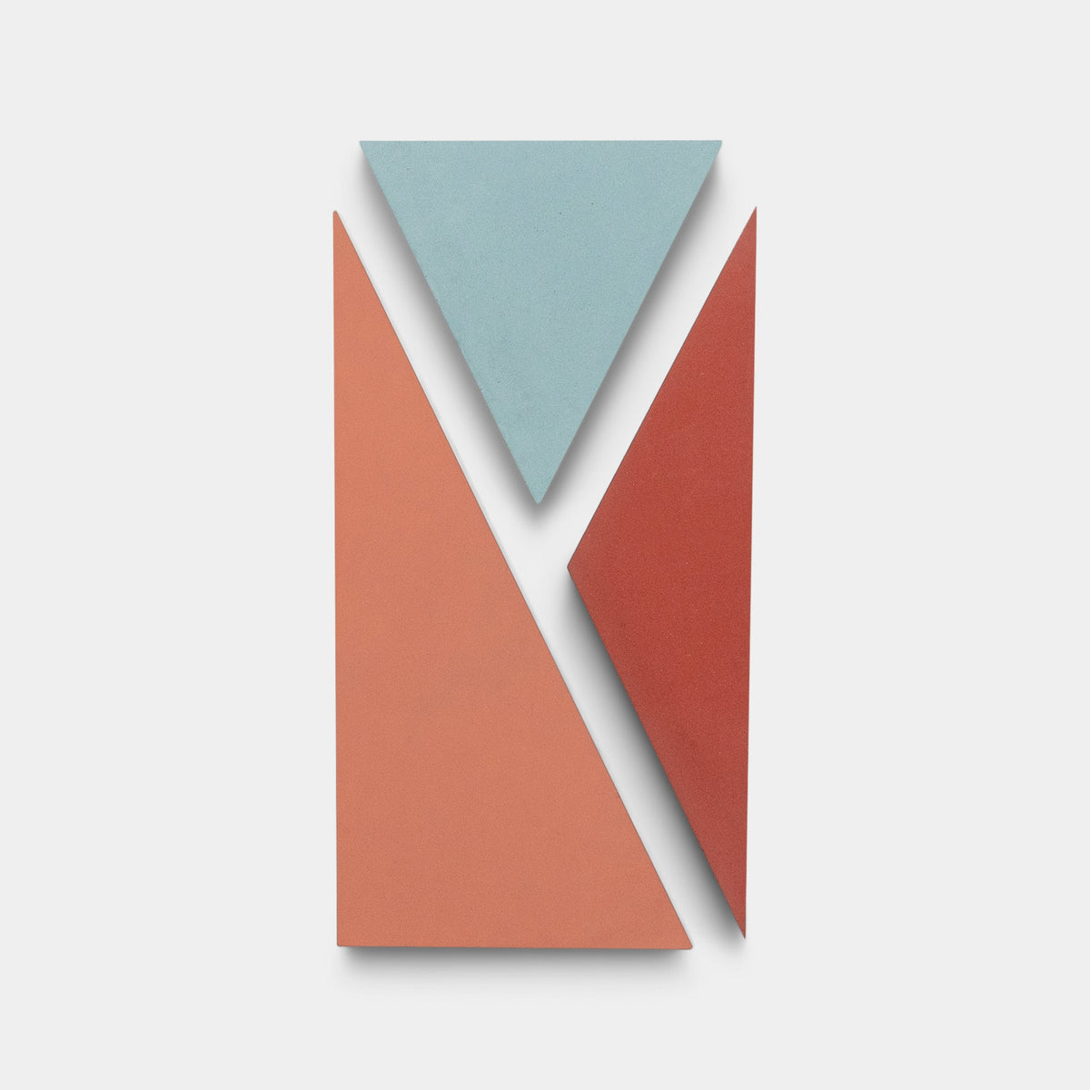 Kepler Set One by Zia Tile: three geometric tiles on white—a large coral triangle, a smaller red triangle, and an upside-down blue triangle—vertically arranged in an abstract pattern echoing Zia Tile’s handmade cement tile style.