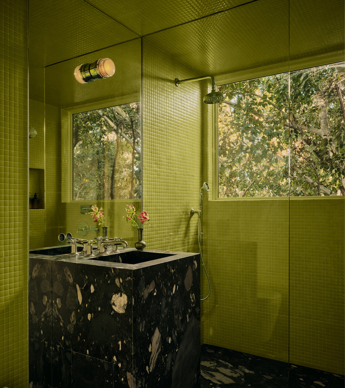 Bathroom walls covered in small, square, lime-green Kiwi 1x1 tiles by Zia Tile, featuring a black marble vanity and a window looking out onto trees.
