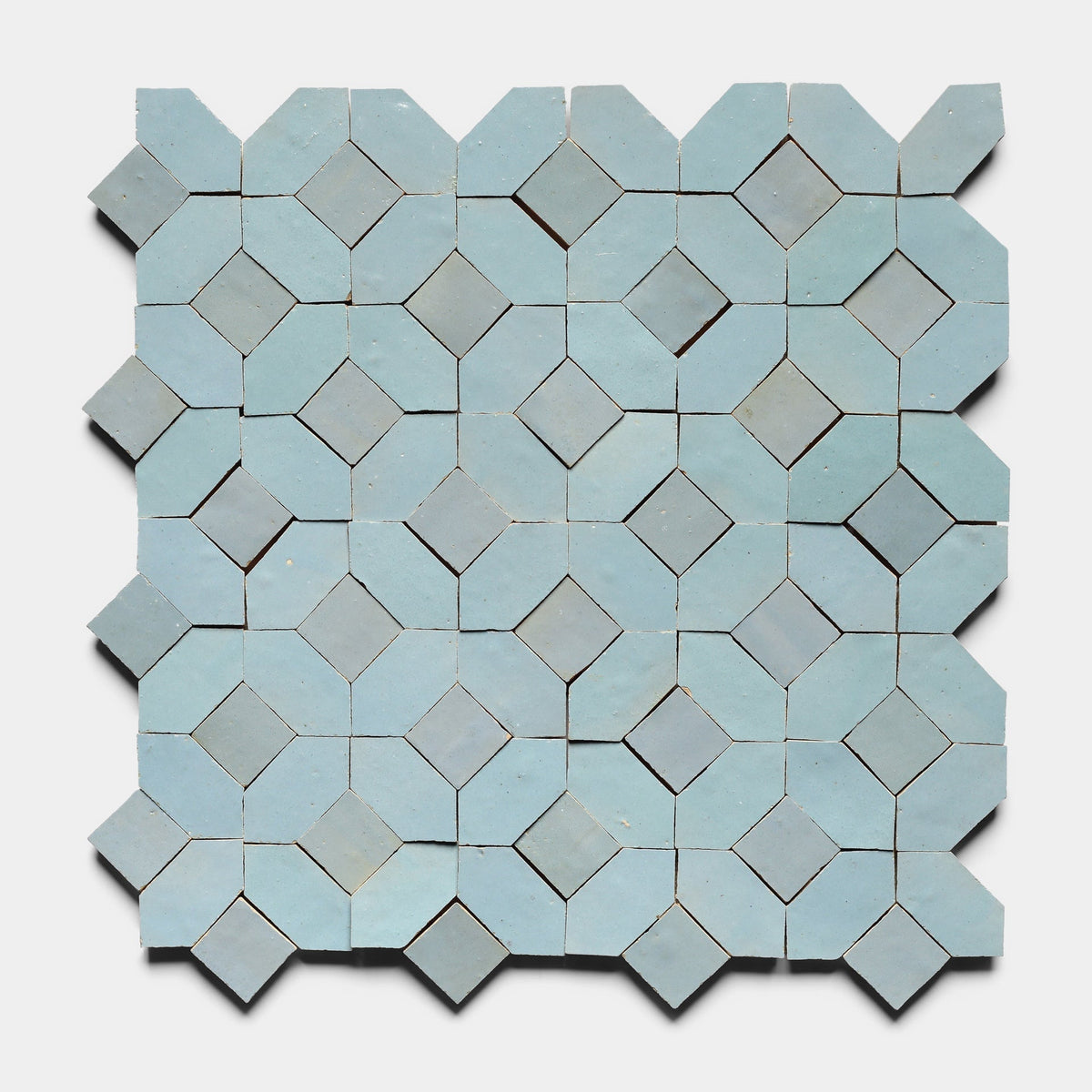 Lattice 5 by Zia Tile features light blue, three-dimensional ceramic tiles arranged in a grid, creating a visually striking, tessellated design with subtle shadows and depth. Sample available.