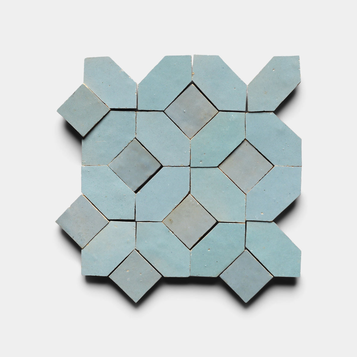 The Lattice 5, Sample by Zia Tile features a geometric pattern of light blue ceramic tiles with diamonds, octagons, and extended corners, creating a dynamic, symmetrical design on a white background.