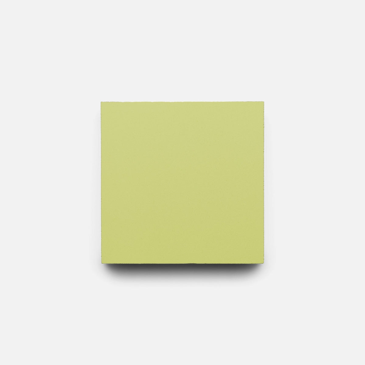 A Lemongrass 4x4 tile sample from Zia Tile, pale yellow-green in color, is centered on a plain white background, evoking the delicate shades of handmade tile.