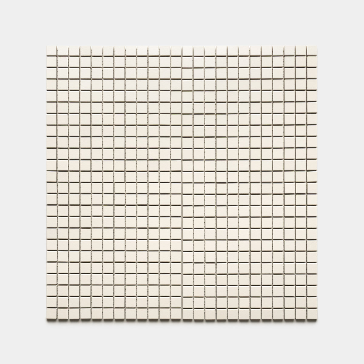 Zia Tile’s Linen 1x1 features small, evenly spaced, square off-white tiles arranged in a grid of rows and columns on a light background.
