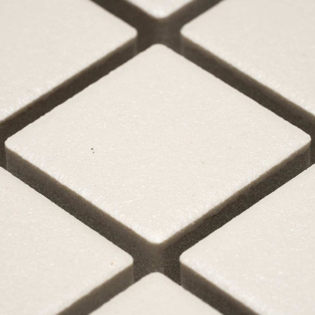 Close-up of Linen 1x1 tiles by Zia Tile—white, square tiles arranged diagonally with narrow gaps and a subtly textured surface.