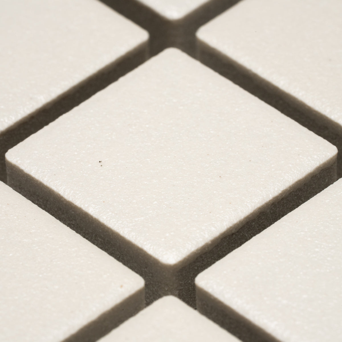 Close-up of Linen 1x1 tiles by Zia Tile—white, square tiles arranged diagonally with narrow gaps and a subtly textured surface.
