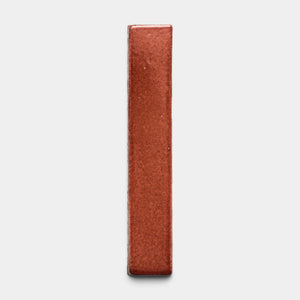The Lupe Mini Bar by Zia Tile stands upright on a plain light gray background, its rectangular reddish-brown shape displayed from the narrow edge for a minimalistic look.