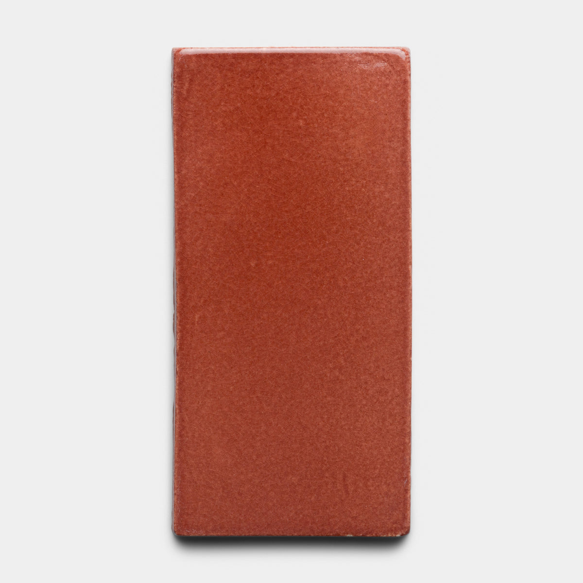 A single Lupe 4x8 Rectangle tile by Zia Tile, featuring a smooth, glossy terracotta finish, is centered on a plain white background.