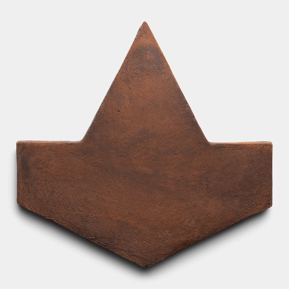The Zia Tile Big Alcazar + Madera sample is a flat, brown, arrowhead-shaped tile with a textured surface, pointed top, and angled lower sides set against a plain white background.