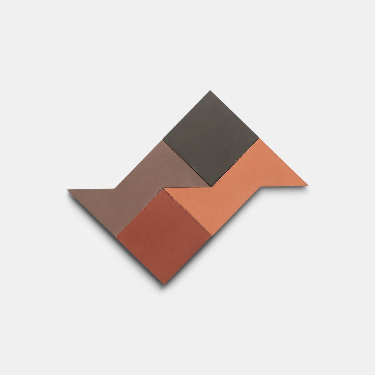 The Manolo Set One, Sample by Zia Tile features four geometric handmade tiles in brown, dark gray, terracotta, and reddish tones arranged in a zigzag pattern on a white background.