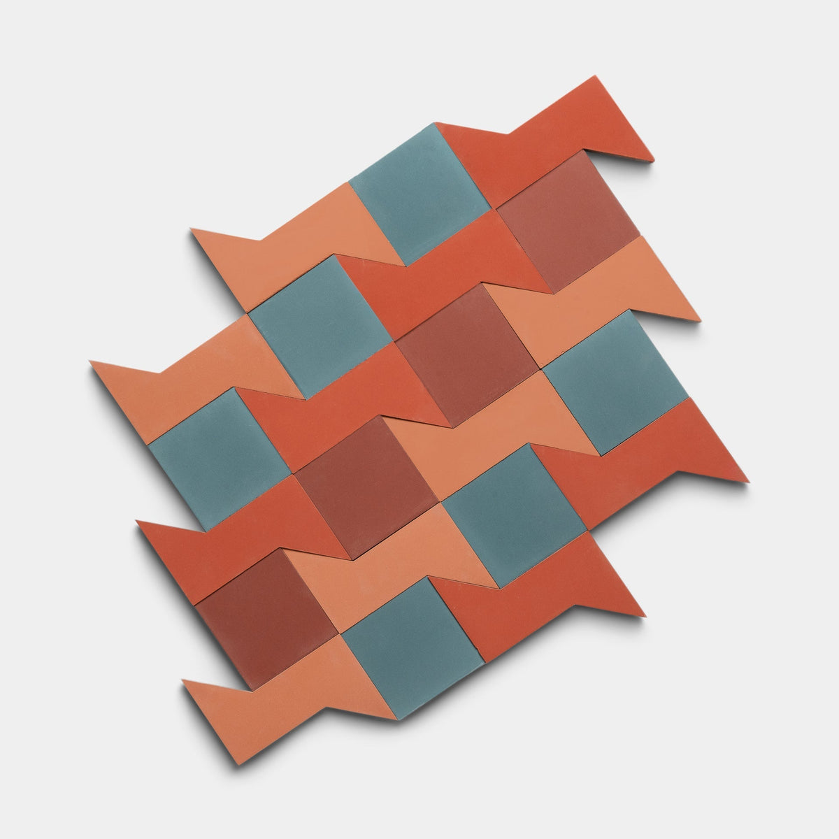 The Manolo Set Two Sample by Zia Tile features interlocking handmade tiles in red, orange, and blue zigzags on white. Some have pointed ends that extend outward for a bold geometric look.