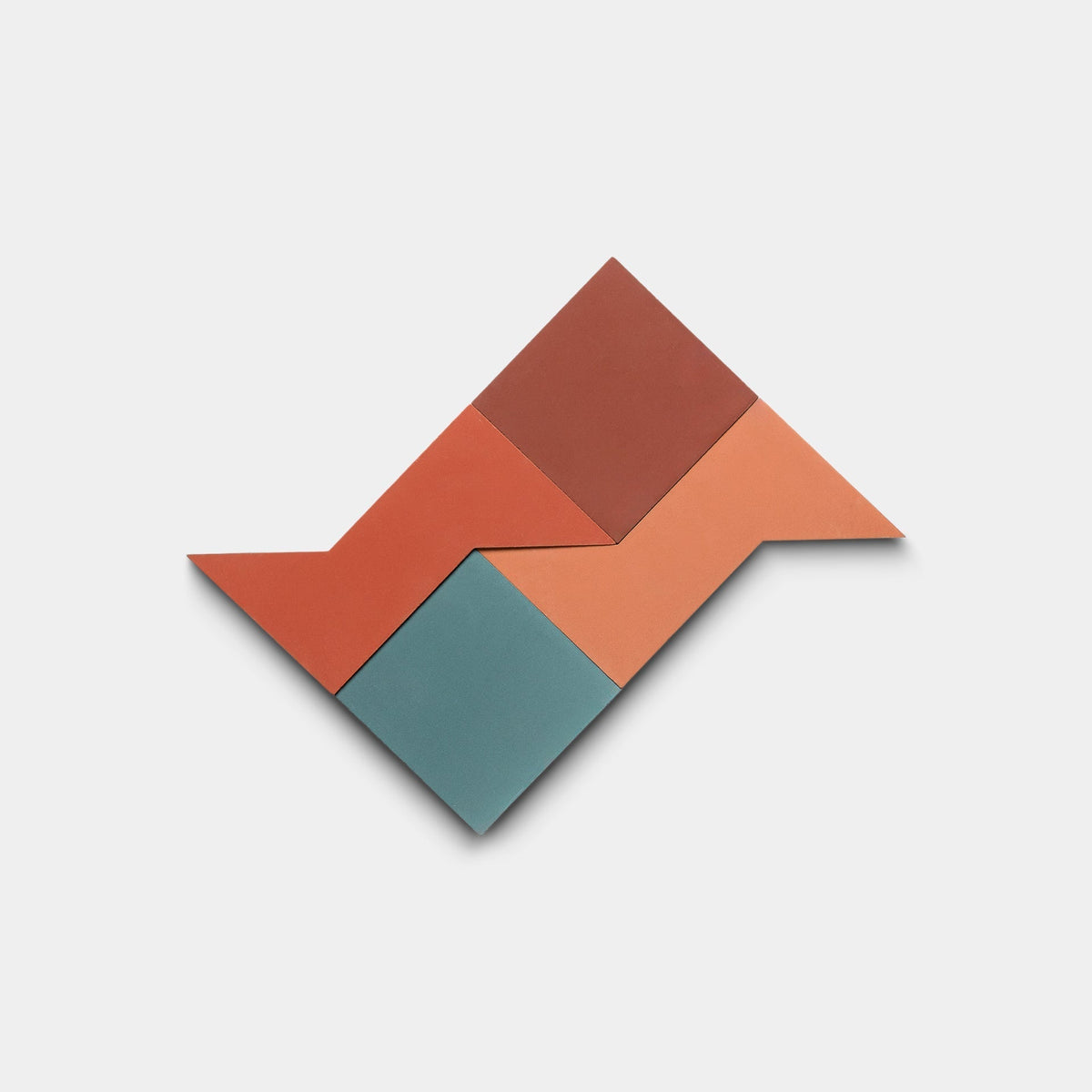 The Manolo Set Two, Sample by Zia Tile features four geometric cement tiles in red, rust, peach, and teal arranged in a zigzag pattern on a plain white background.