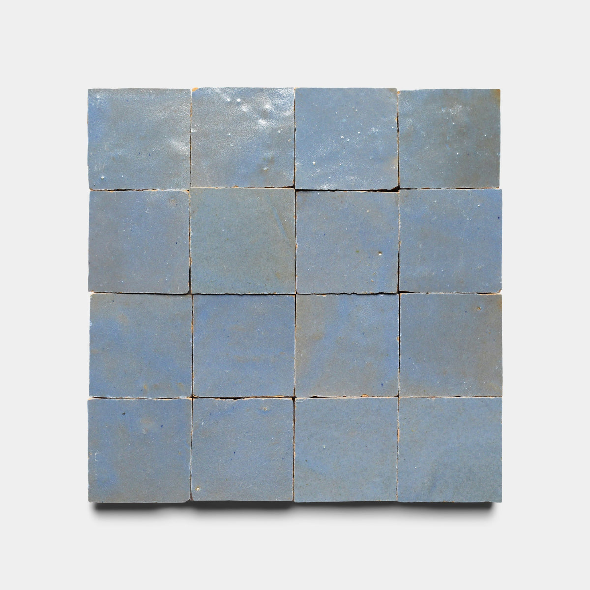 A set of sixteen Zia Tile Maya Blue 2x2 handmade tiles, each with a matte glaze and unique texture, neatly arranged on a plain white background.