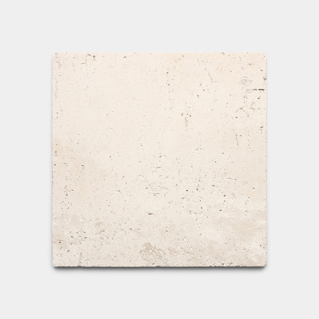 Zia Tile Mesa 6x6 sample: a beige square stone tile with a slightly rough texture, natural imperfections, and subtle surface variations, shown on a plain light gray background.