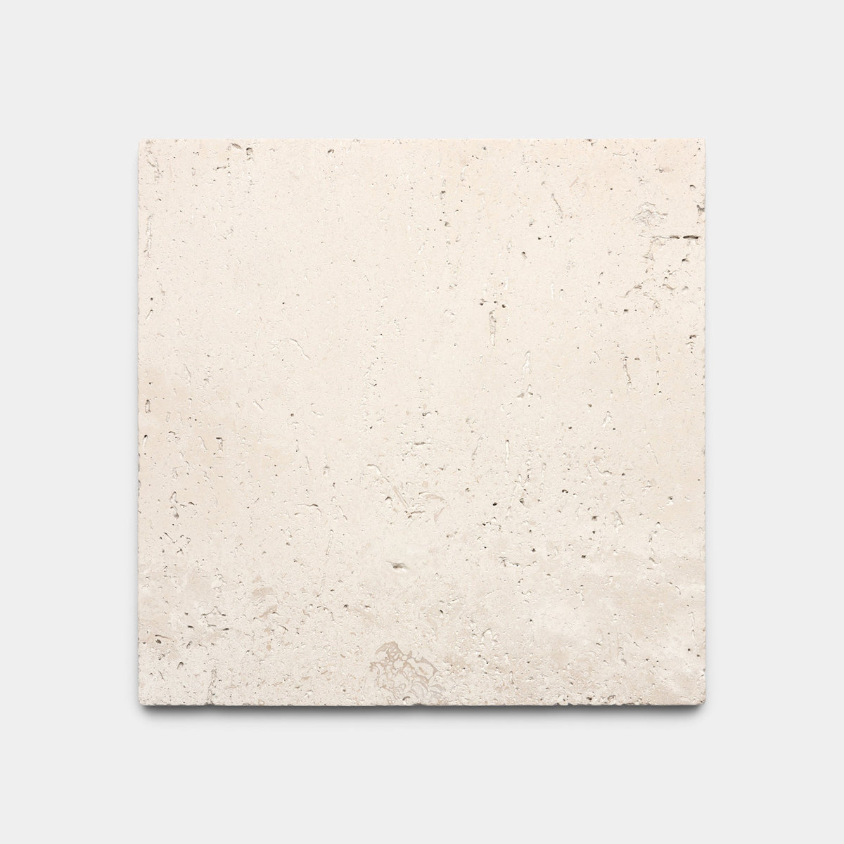 Zia Tile Mesa 6x6 sample: a beige square stone tile with a slightly rough texture, natural imperfections, and subtle surface variations, shown on a plain light gray background.
