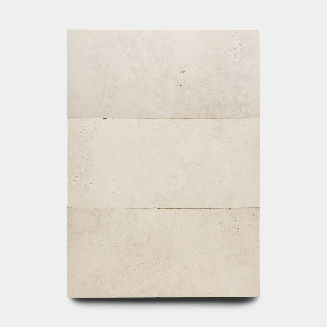 Three Mesa 12x24 rectangular beige tiles from Zia Tile are stacked vertically against a plain white background, showcasing subtle natural texture and slight color variations.