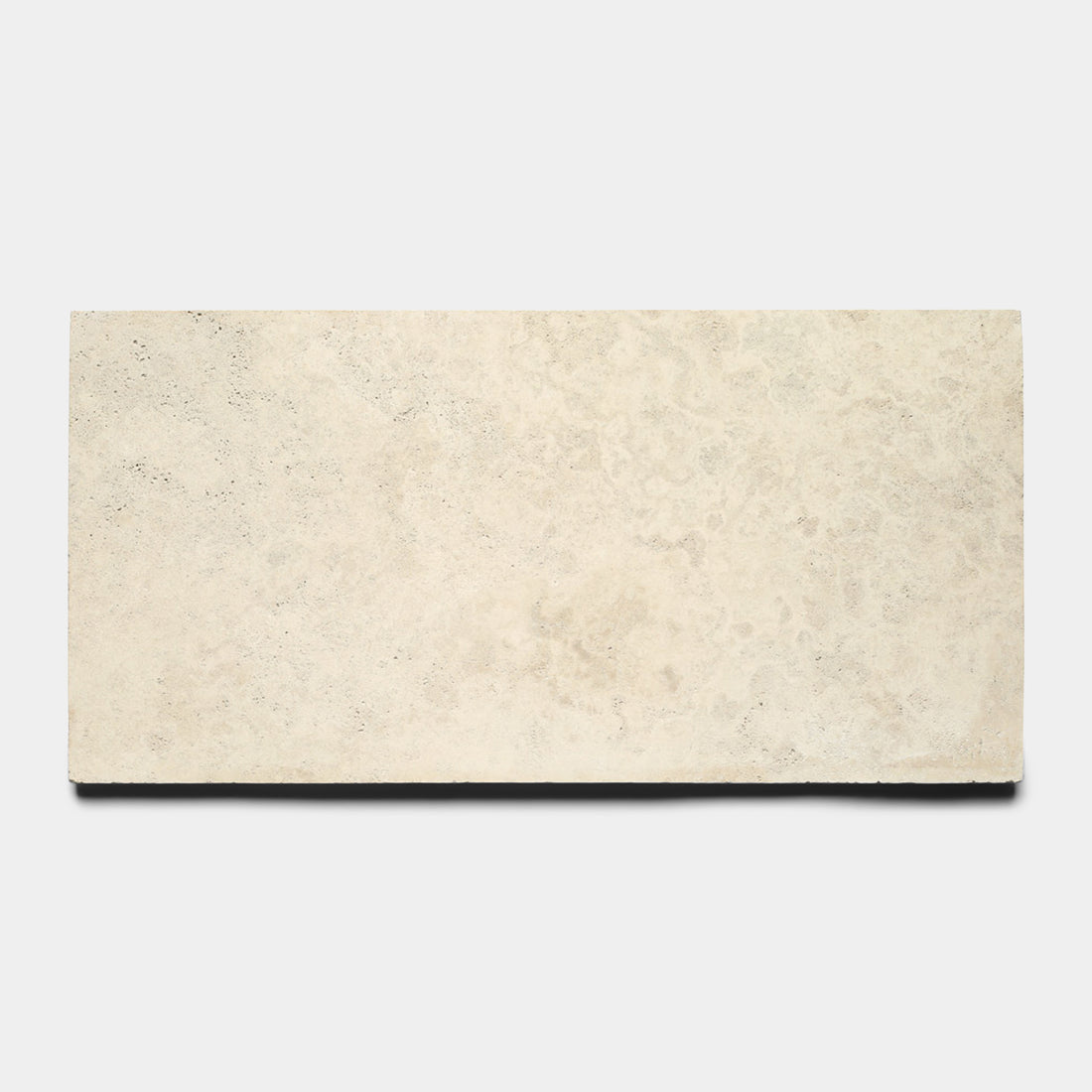 The Mesa 12x24 by Zia Tile is a rectangular, light beige Mexican Cantera stone tile with a smooth, slightly textured surface, shown against a plain white background.
