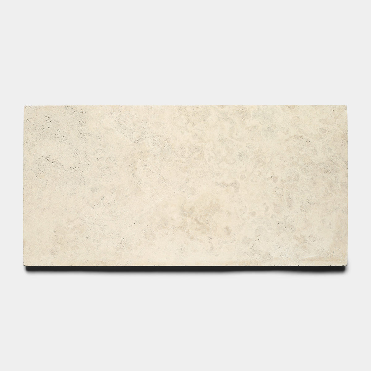 The Mesa 12x24 by Zia Tile is a rectangular, light beige Mexican Cantera stone tile with a smooth, slightly textured surface, shown against a plain white background.