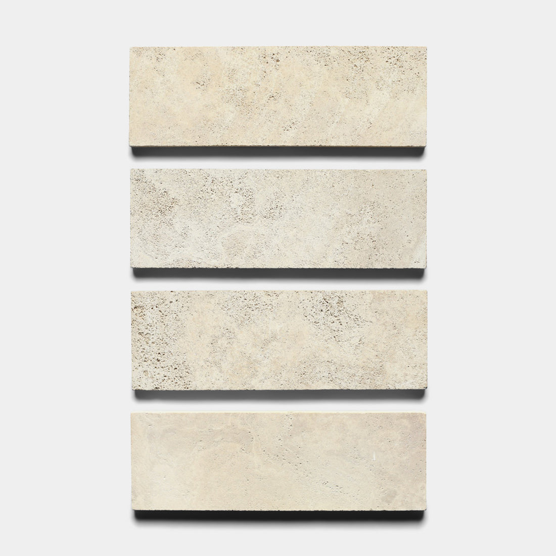 Four rectangular Mesa 4x12 tiles by Zia Tile are arranged vertically on a white background, each beige tile evenly spaced and showing the distinct textures of natural volcanic stone.