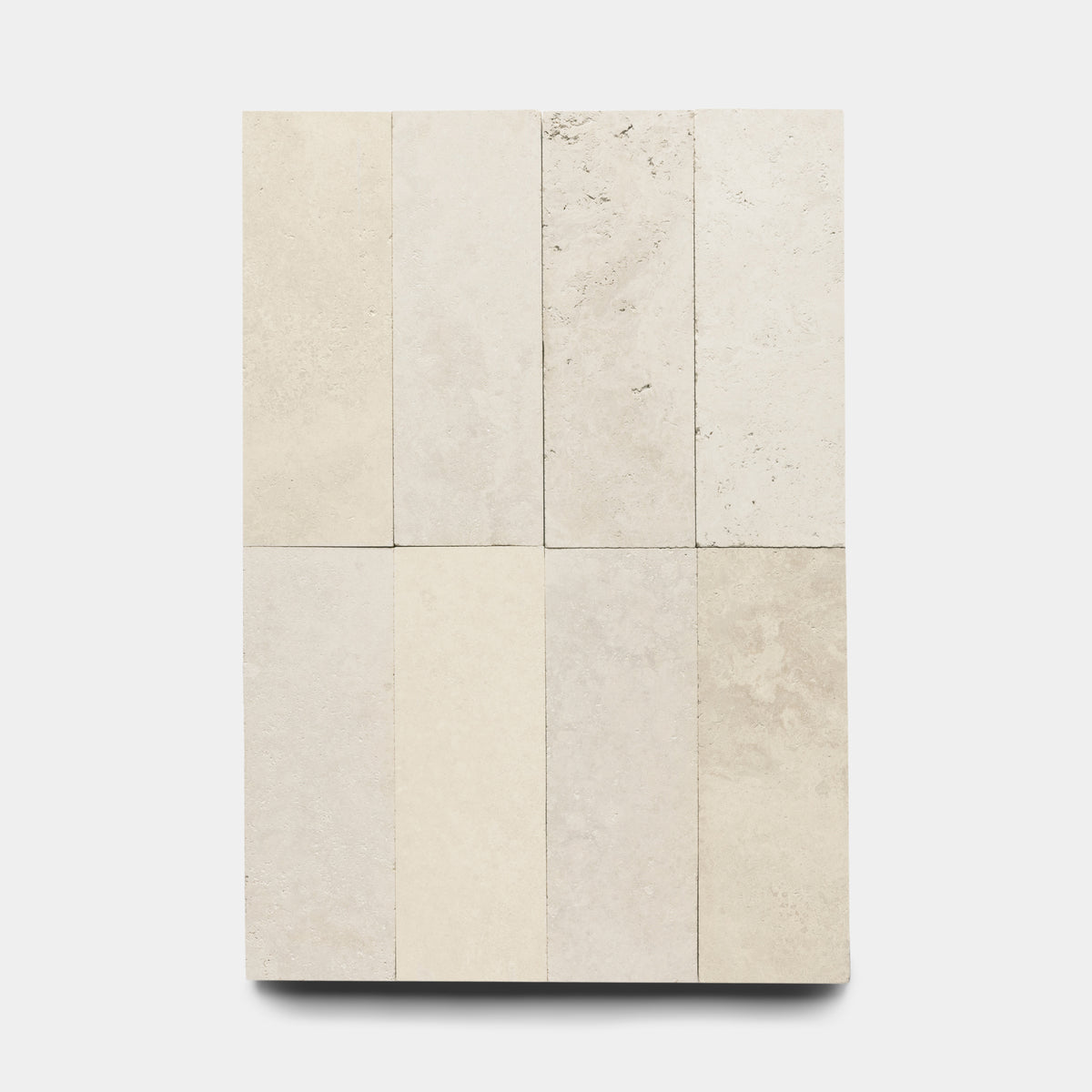 Eight rectangular Mesa 4x12 tiles by Zia Tile are arranged in two rows of four on a plain white background, each showing subtle shade and texture variations typical of natural volcanic stone.