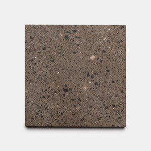 The Zia Tile Moab 12x12 is a square brown handmade tile featuring black and light brown speckles, inspired by traditional Moroccan designs, displayed on a plain white background.