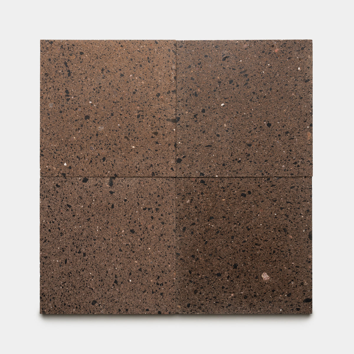 Four Moab 12x12 tiles by Zia Tile, displaying a rich brown volcanic stone texture with black and light speckles, are arranged in a square grid on a white background, evoking the artisanal charm of handmade tile.
