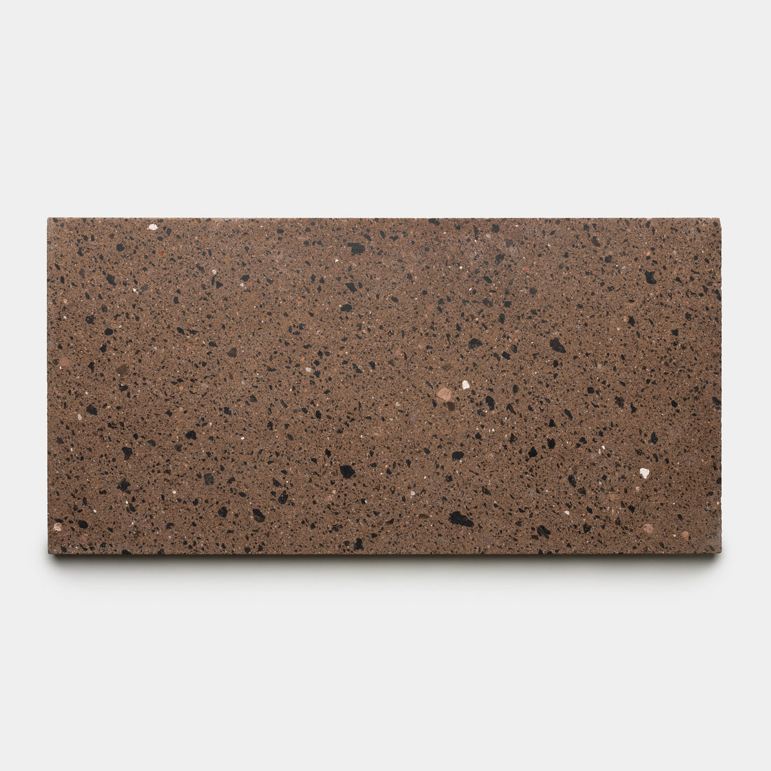 The Moab 12x24 by Zia Tile is a rectangular slab of chocolate brown terrazzo tile featuring small black, dark brown, and white speckles, shown against a plain light gray background.