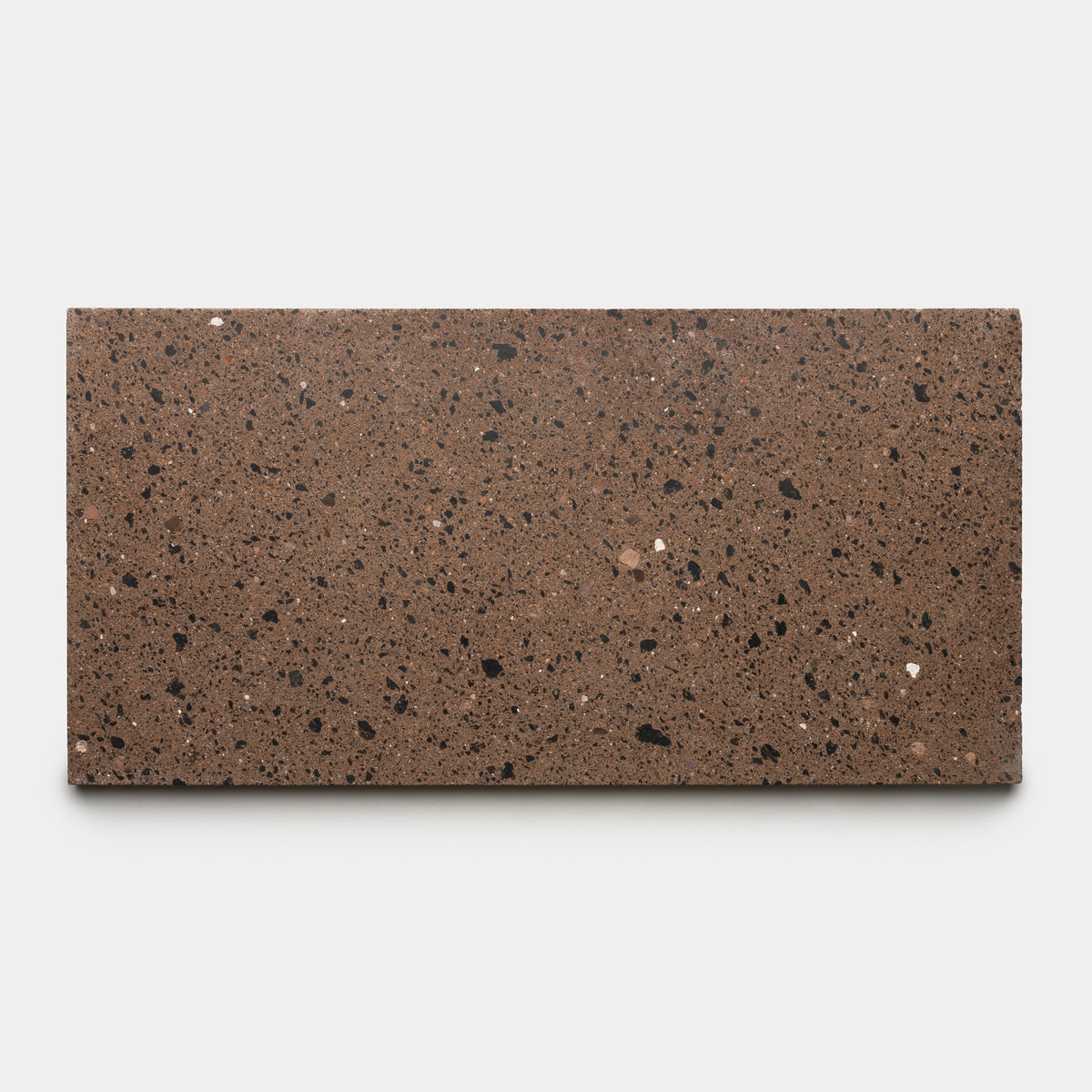 The Moab 12x24 by Zia Tile is a rectangular slab of chocolate brown terrazzo tile featuring small black, dark brown, and white speckles, shown against a plain light gray background.