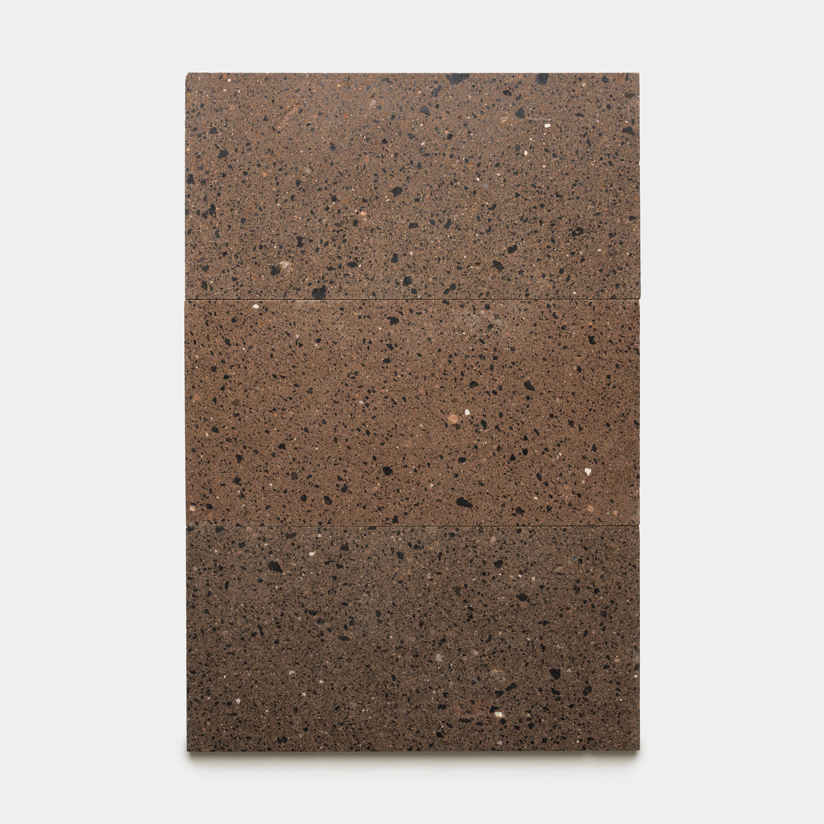 Four Moab 12x24 rectangular brown stone tiles with black speckles from Zia Tile are arranged vertically against a plain white background, highlighting the natural beauty and unique character of handmade tile.