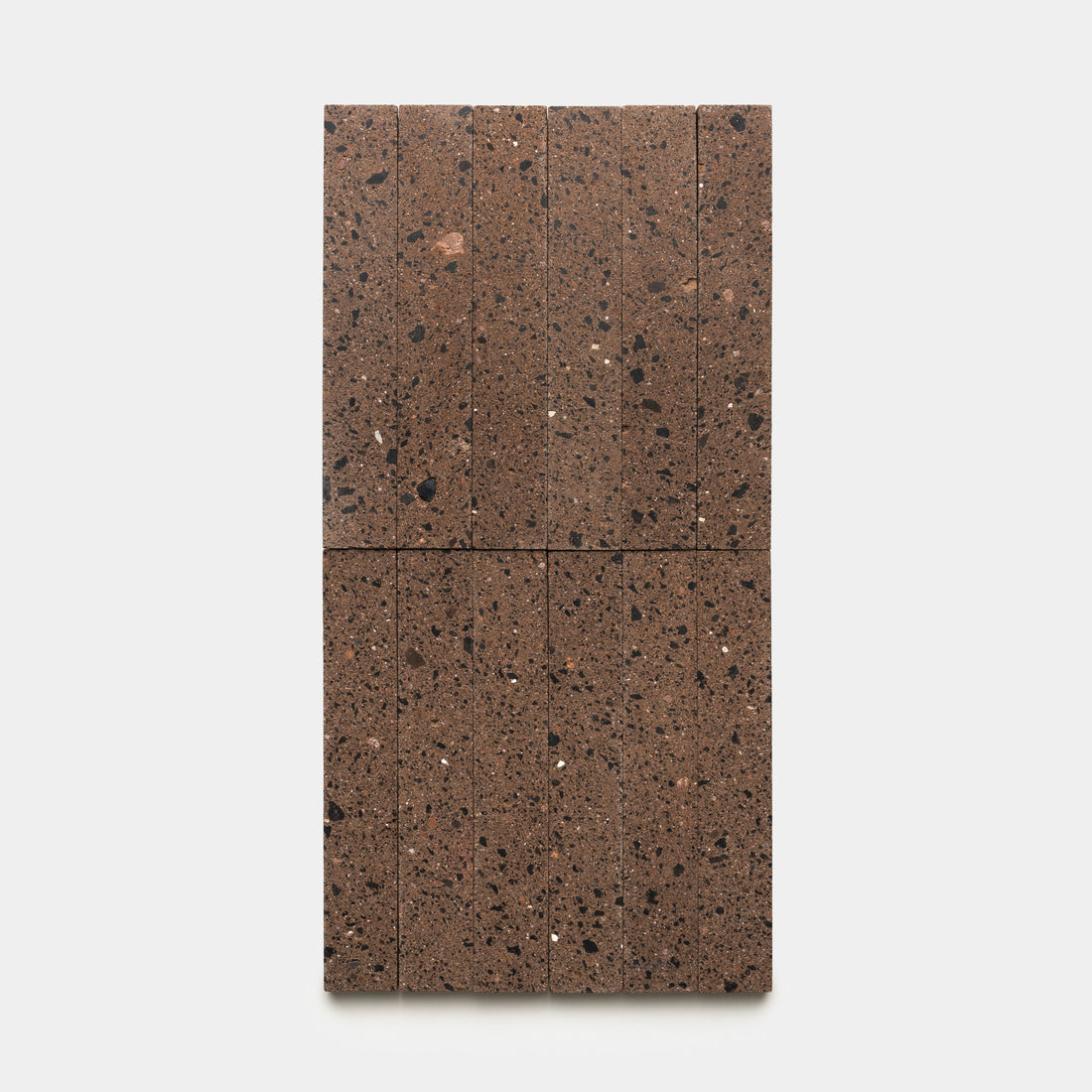 The Moab 2x12 terrazzo tile by Zia Tile features a rectangular brown design divided into eight sections, showcasing dark and light speckled patterns, displayed on a plain white background.