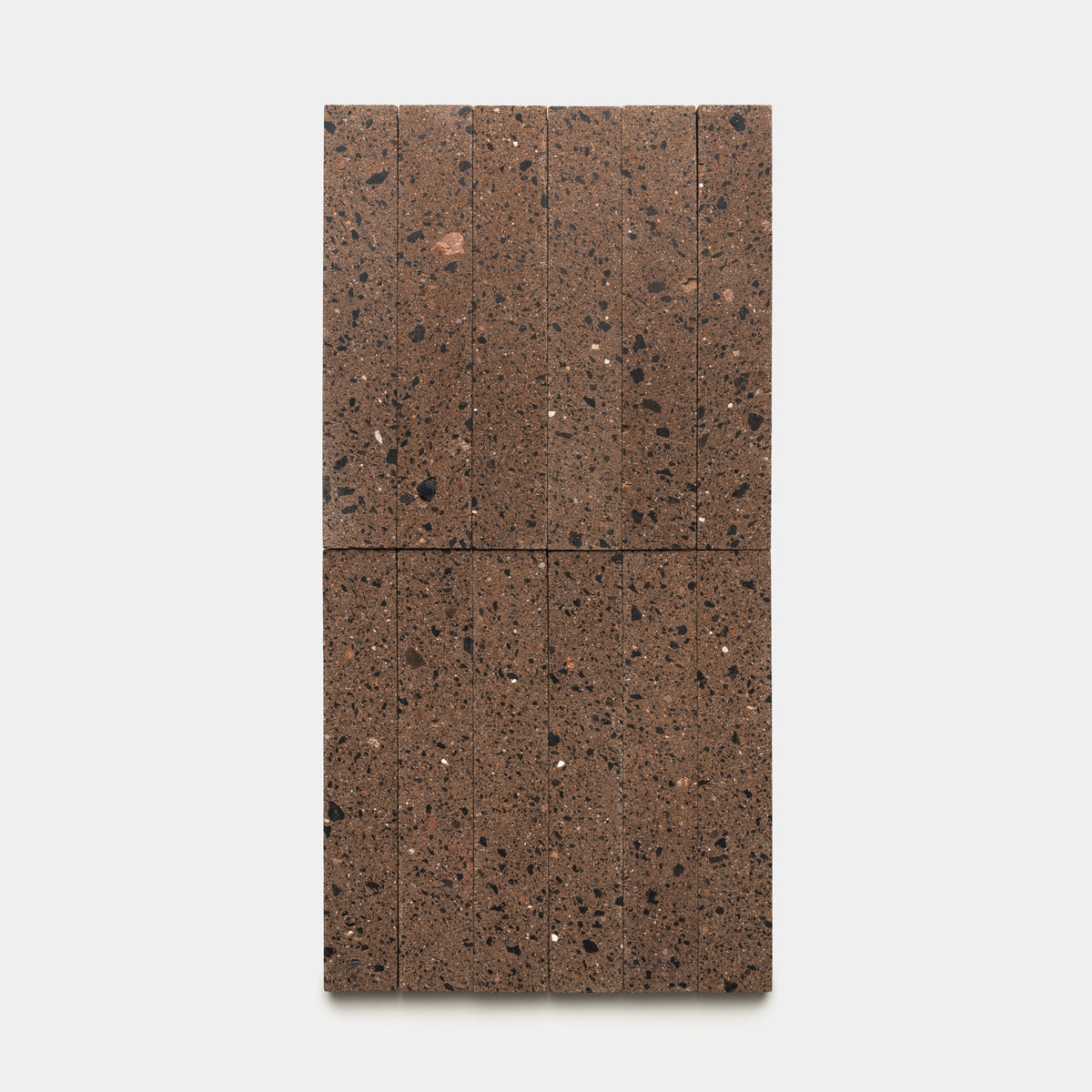 The Moab 2x12 terrazzo tile by Zia Tile features a rectangular brown design divided into eight sections, showcasing dark and light speckled patterns, displayed on a plain white background.