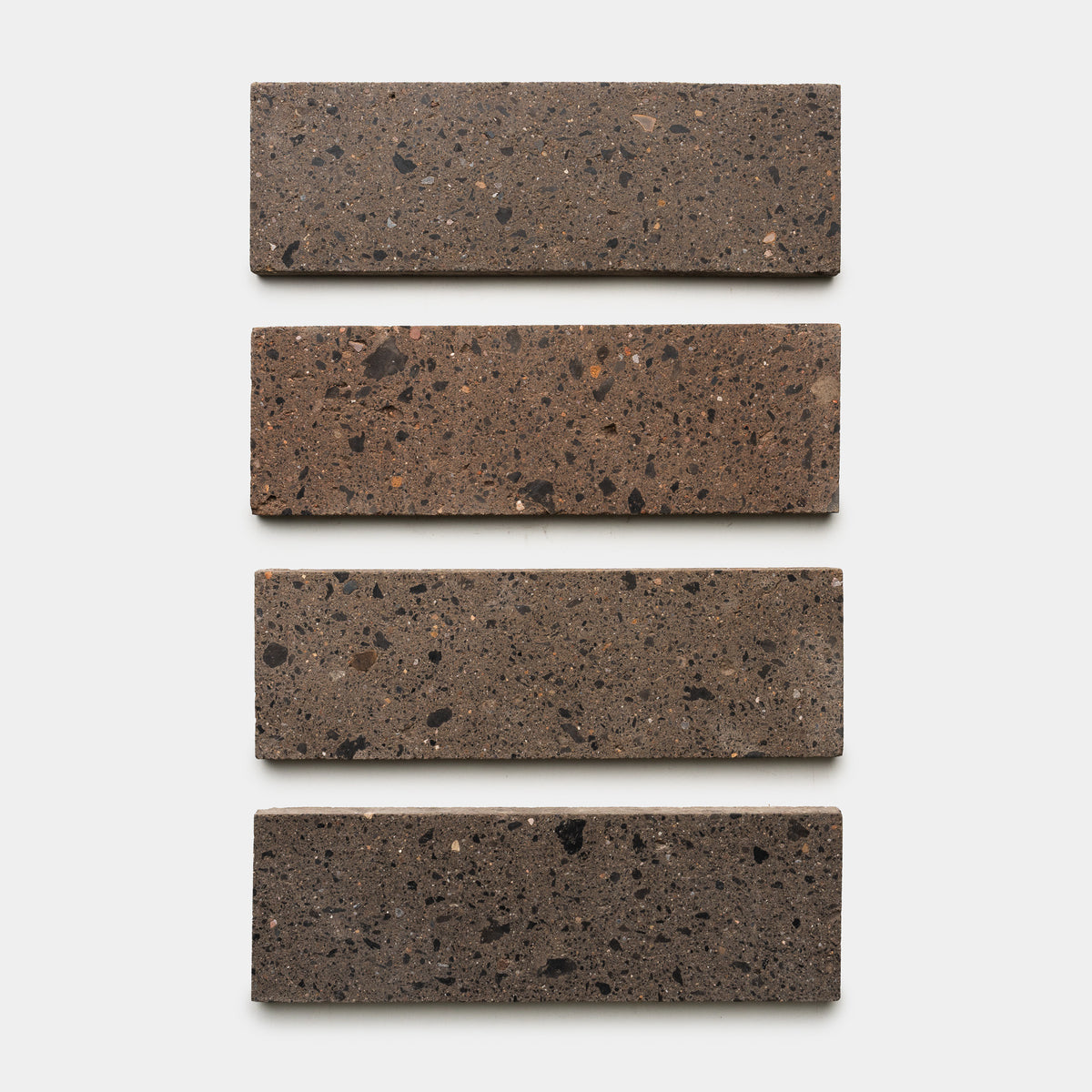 Four rectangular Moab 4x12 brown terrazzo tiles with dark speckles from Zia Tile are arranged in a vertical column on a plain white background, highlighting their contemporary style.
