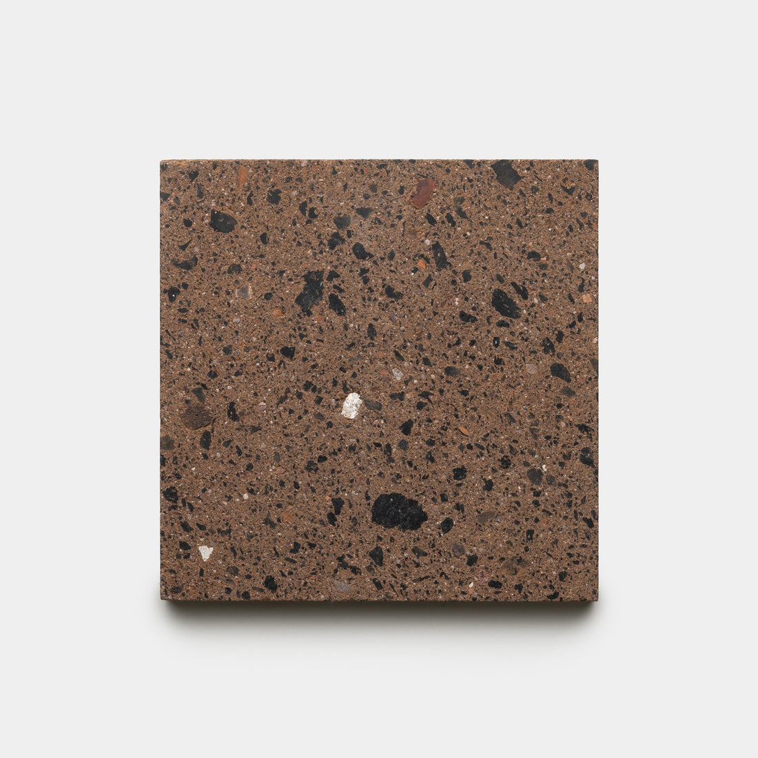 A sample of Zia Tile’s Moab 6x6 tile, featuring a square shape with a brown base and scattered black and gray speckles, displayed against a plain white background.