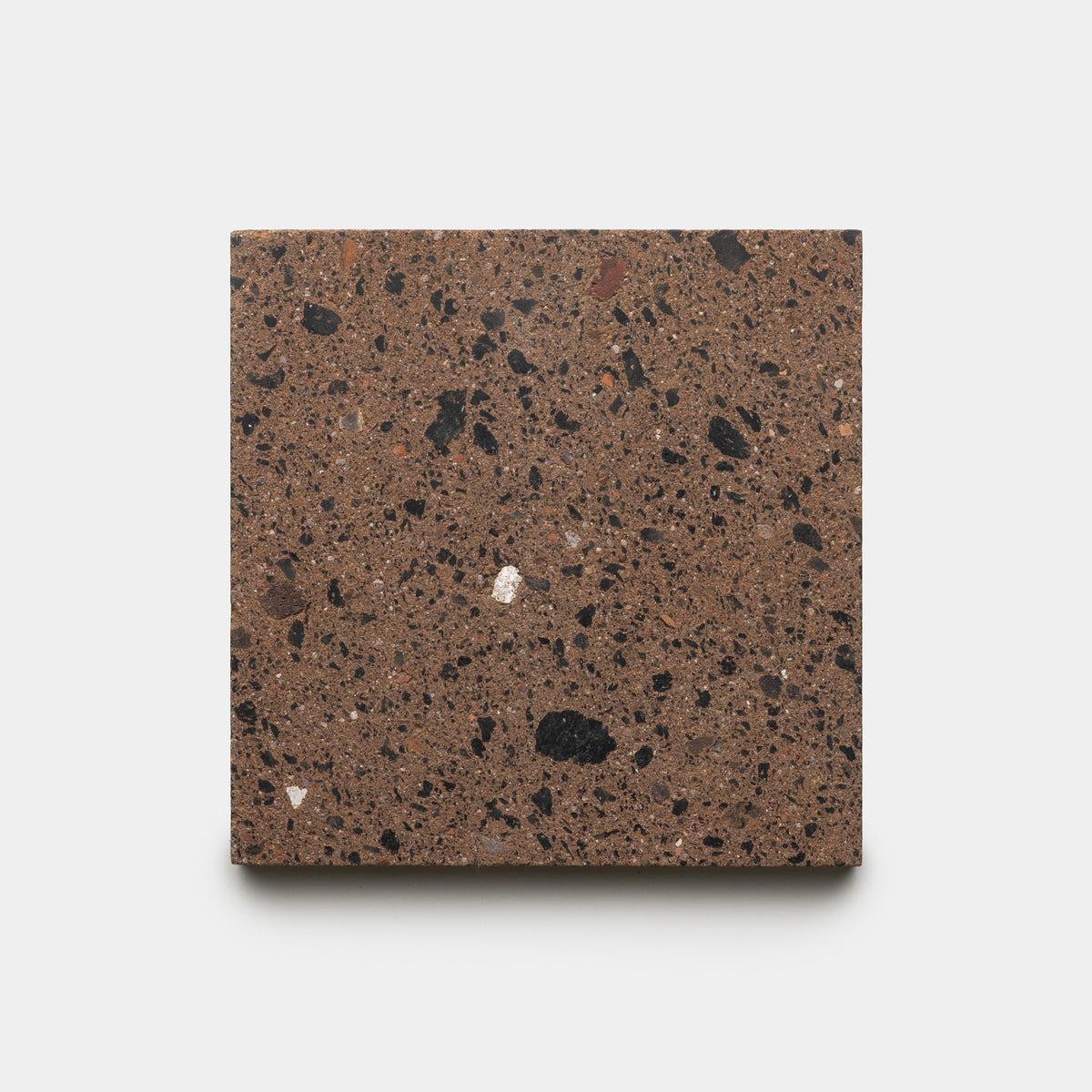 A sample of Zia Tile’s Moab 6x6 tile, featuring a square shape with a brown base and scattered black and gray speckles, displayed against a plain white background.