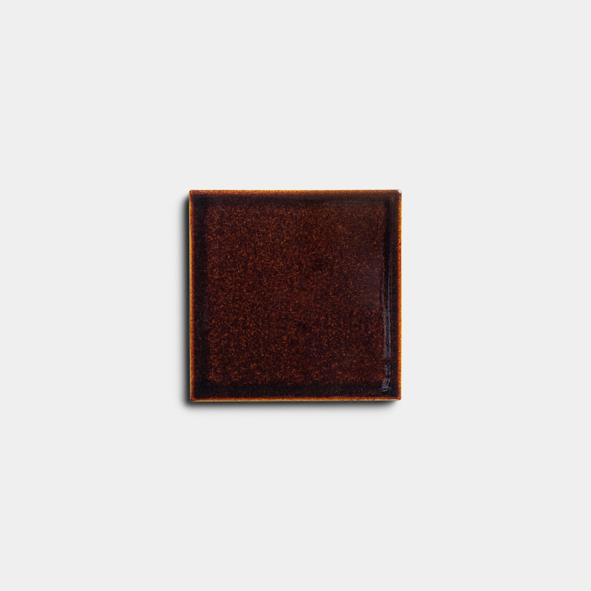 The Molasses 4x4 sample by Zia Tile is a single square ceramic tile featuring a glossy, dark reddish-brown finish and subtly textured surface, displayed against a plain white background.