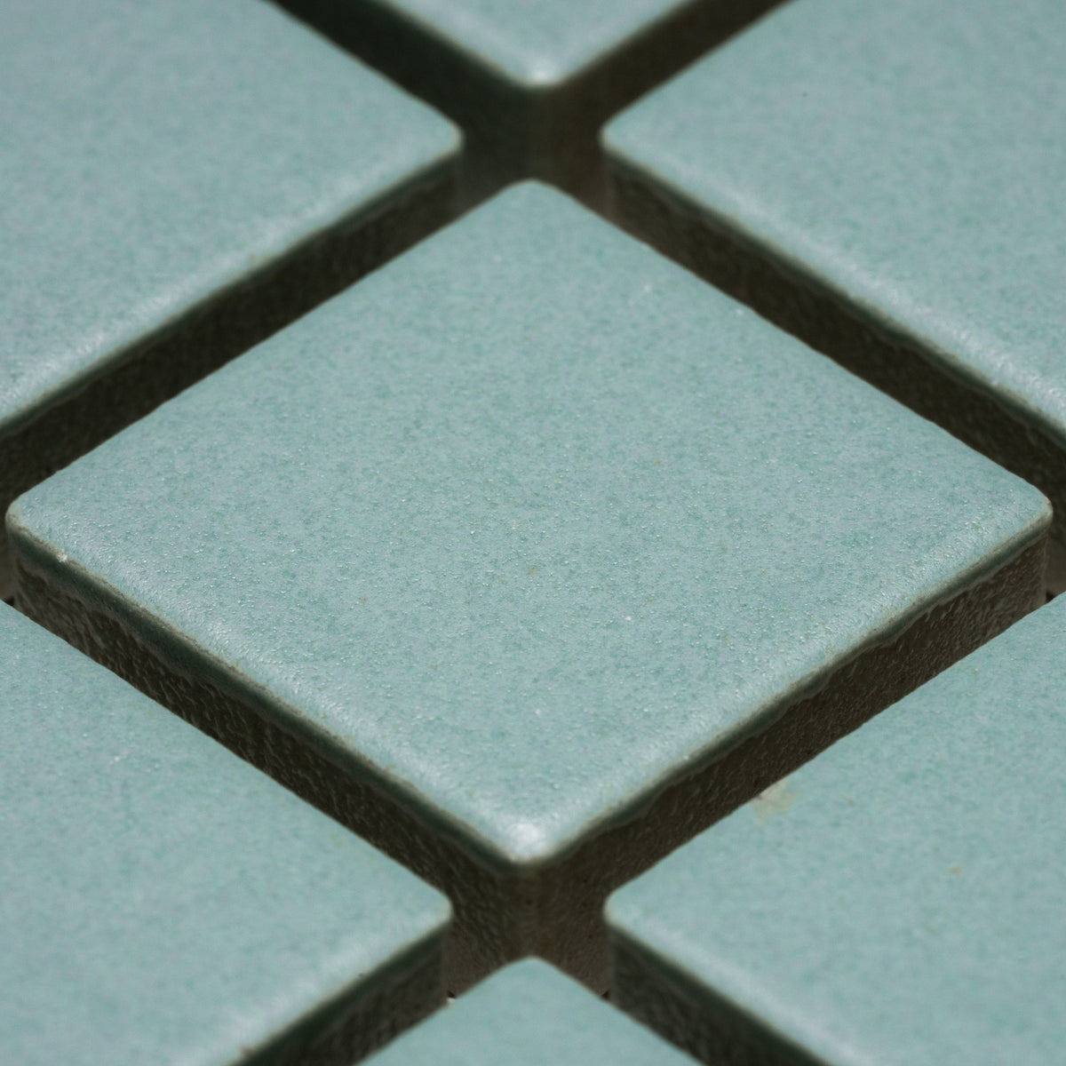 Close-up of Zia Tile’s Moonlight 1x1 light blue-green square ceramic tiles arranged in a grid with visible grout lines.
