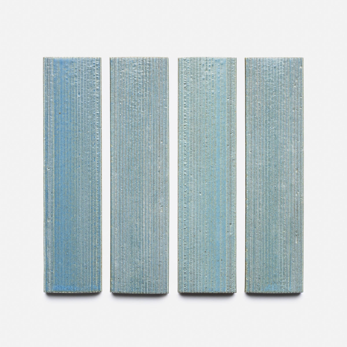 Four vertically aligned Morning Light + Etched samples by Zia Tile, each rectangular and textured with fine horizontal and vertical lines, are evenly spaced in a row against a plain white background.