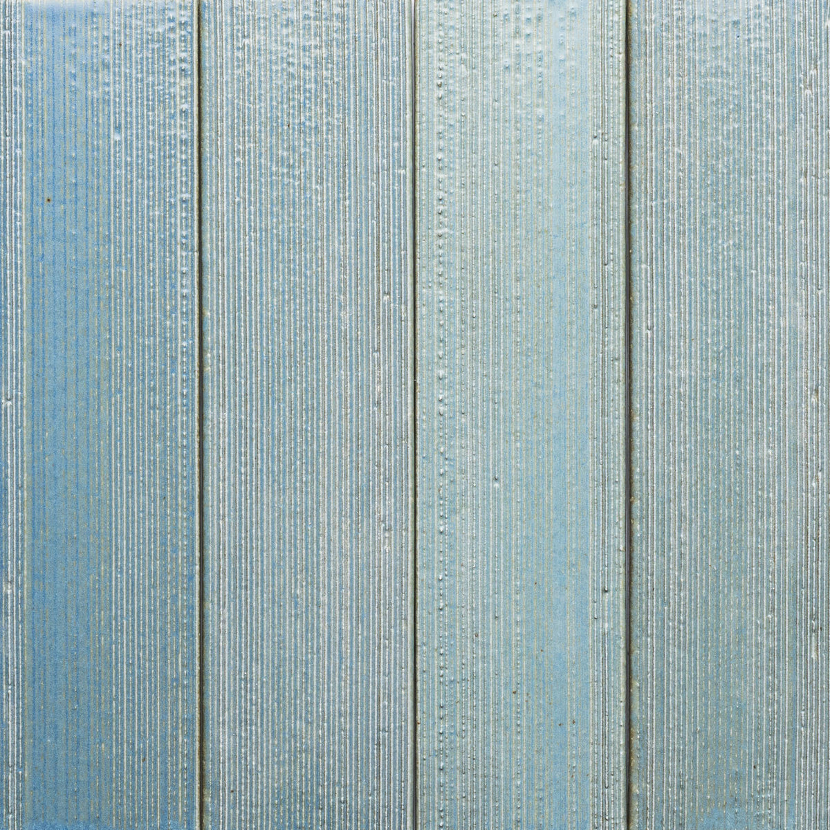 Morning Light + Etched sample by Zia Tile features light blue wooden panels with a textured vertical grain, subtle weathering, and thin gaps.