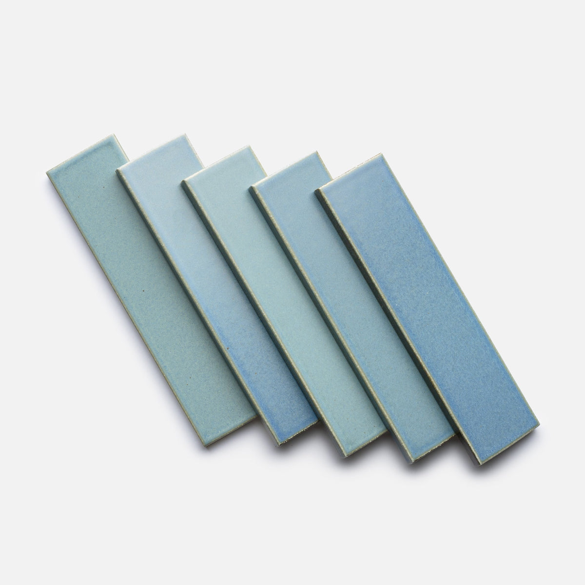 Five Morning Light + Flat, Sample tiles by Zia Tile are arranged in a fanned-out pattern on a white background, displaying a gradient of blue shades from light to dark.