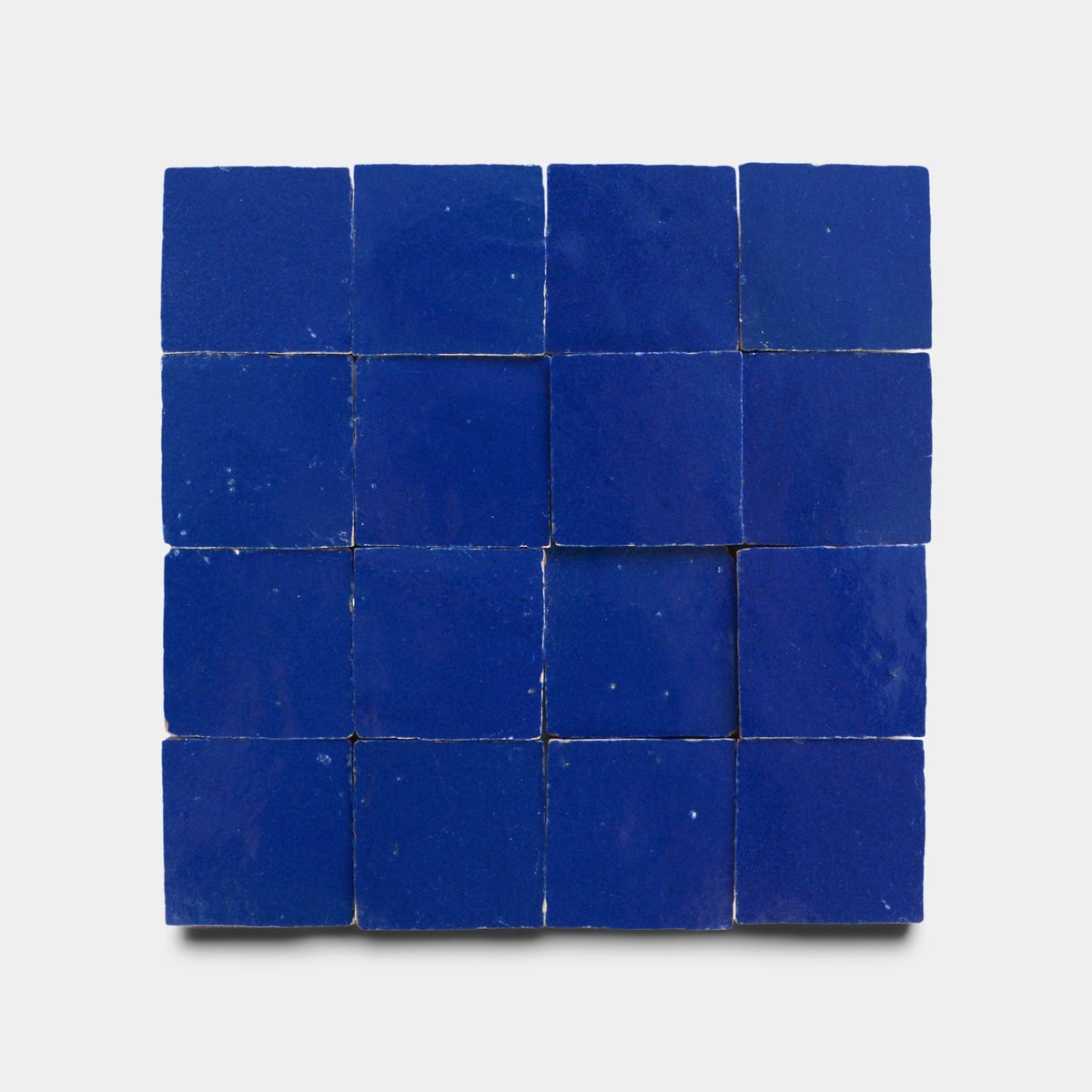 A 4x4 grid of Maya Blue 2x2 ceramic tiles by Zia Tile is displayed on a plain white background, providing a vivid sample of this classic color.