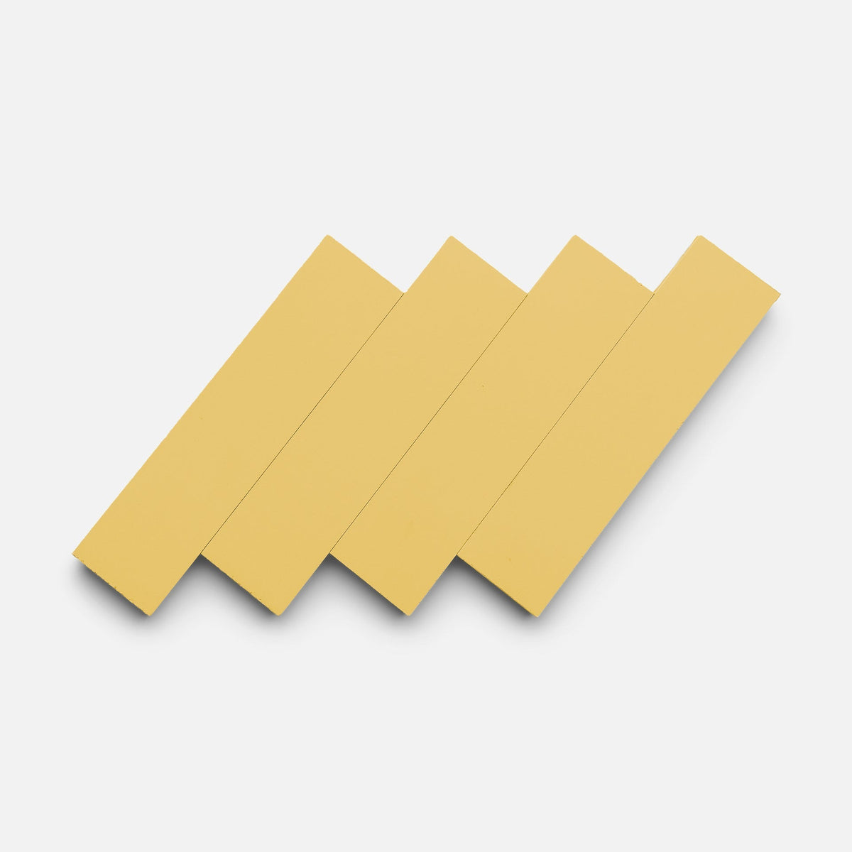 Four Mustard 2x8 tile samples by Zia Tile are arranged diagonally and overlapping in a zigzag pattern on a white background.
