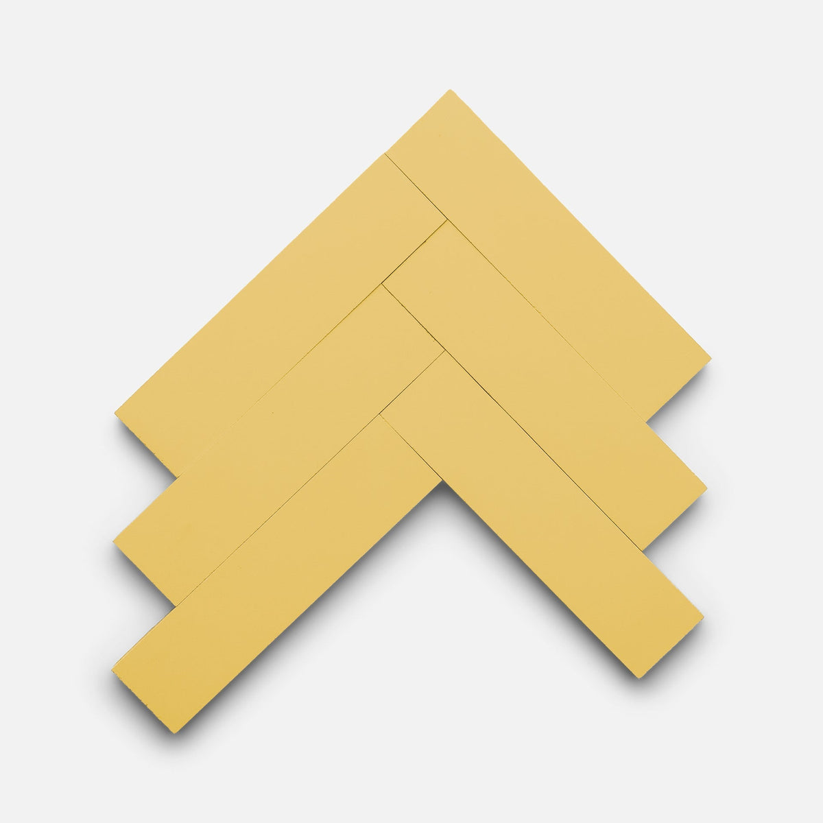 Five Mustard 2x8 tiles by Zia Tile are arranged in a diagonal herringbone pattern on a plain white background.