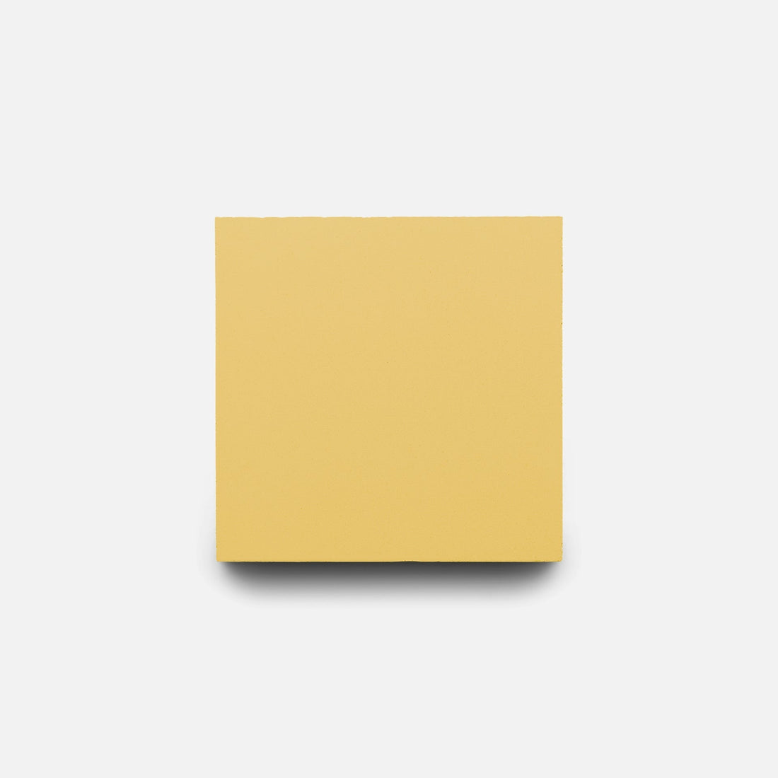 A single Zia Tile Mustard 4x4 tile is centered on a plain white background, casting a faint shadow below it and resembling a yellow square sticky note.