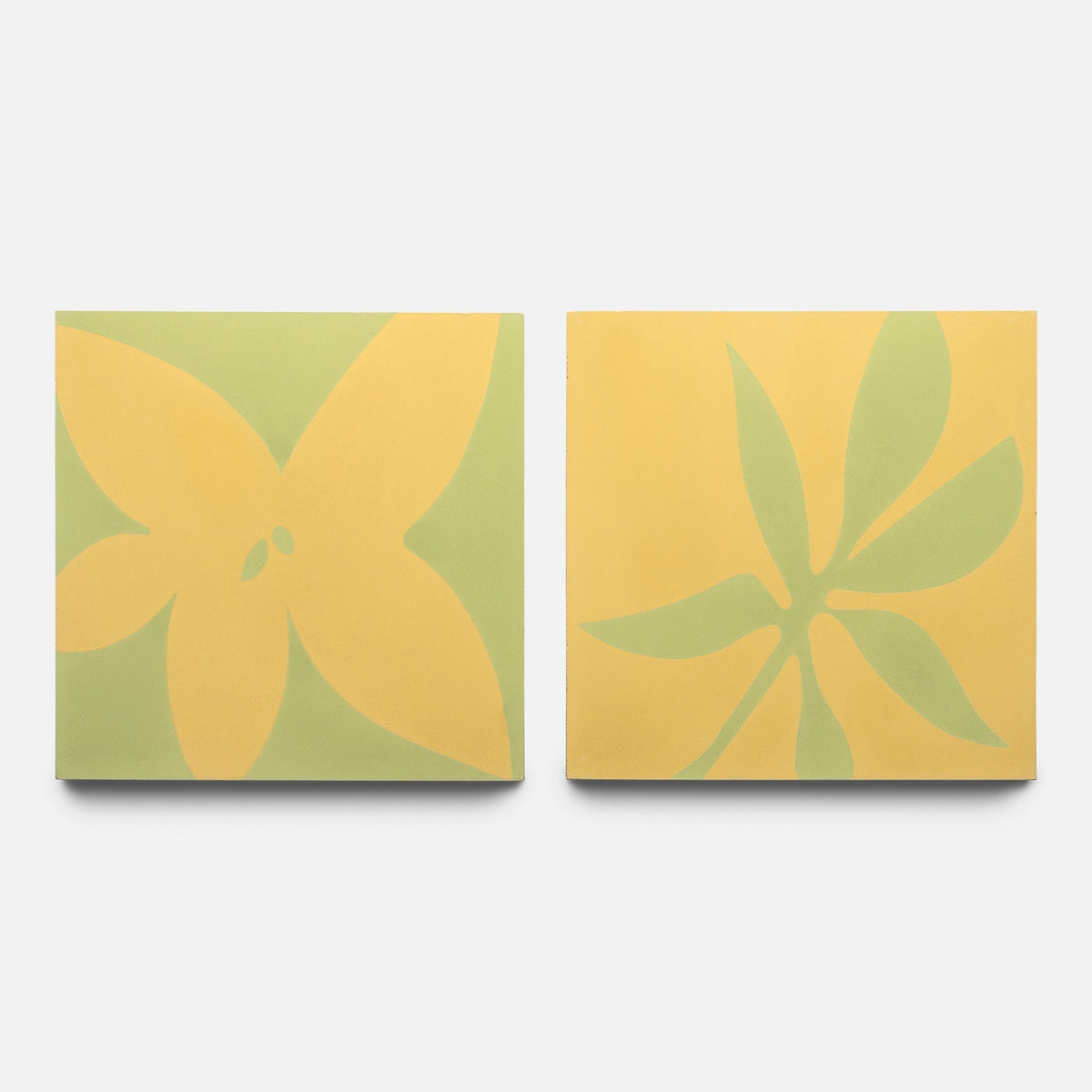 The Flora 8x8 Set Mustard + Lemongrass Sample by Zia Tile features two rectangular canvases: one with a yellow four-petal flower on pale green, and the other with green leaves on yellow backgrounds.