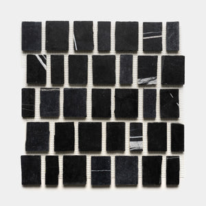 Scarpa in Nero Marquina by Zia Tile features a 5x5 sheet of black marble tiles, each with unique white veining, mounted on a white mesh backing.