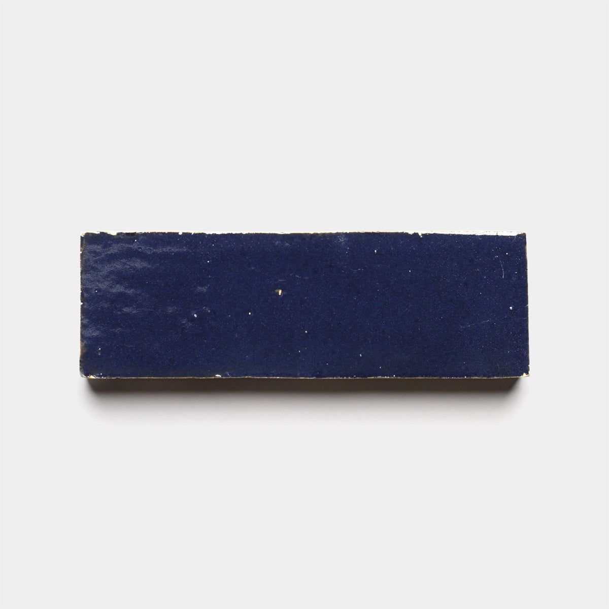 The Night Blue 2x6 ceramic tile sample by Zia Tile, featuring a glossy finish, is displayed against a plain white background.
