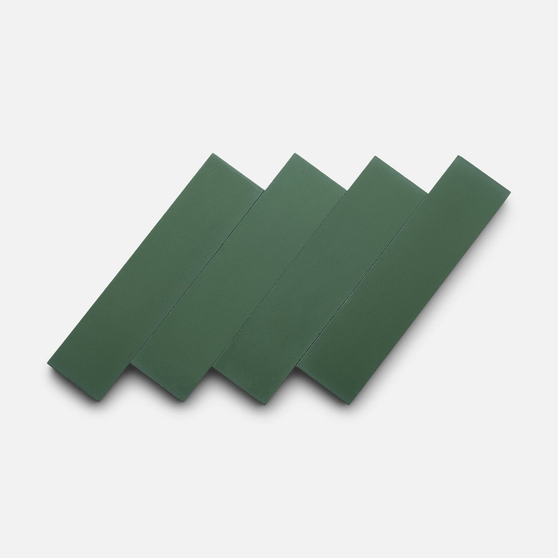 Four Noble Green 2x8 matte tiles by Zia Tile, rectangular and dark green, are handmade and arranged diagonally overlapping each other on a plain white background.