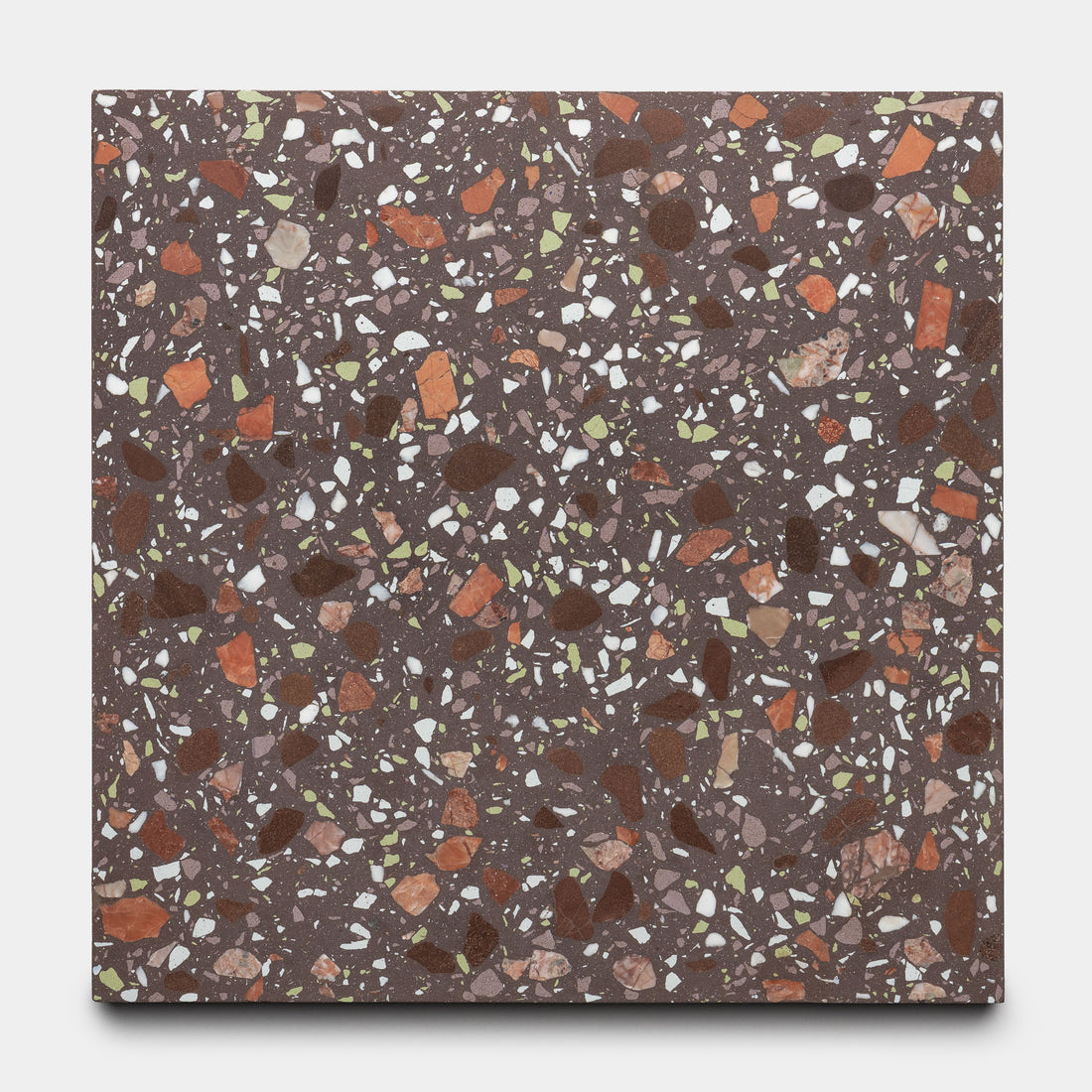 The Nocino 12x12 tile by Zia Tile features a dark brown base with white, red, orange, and green chips in varying sizes and shapes for a vibrant, speckled mosaic pattern.