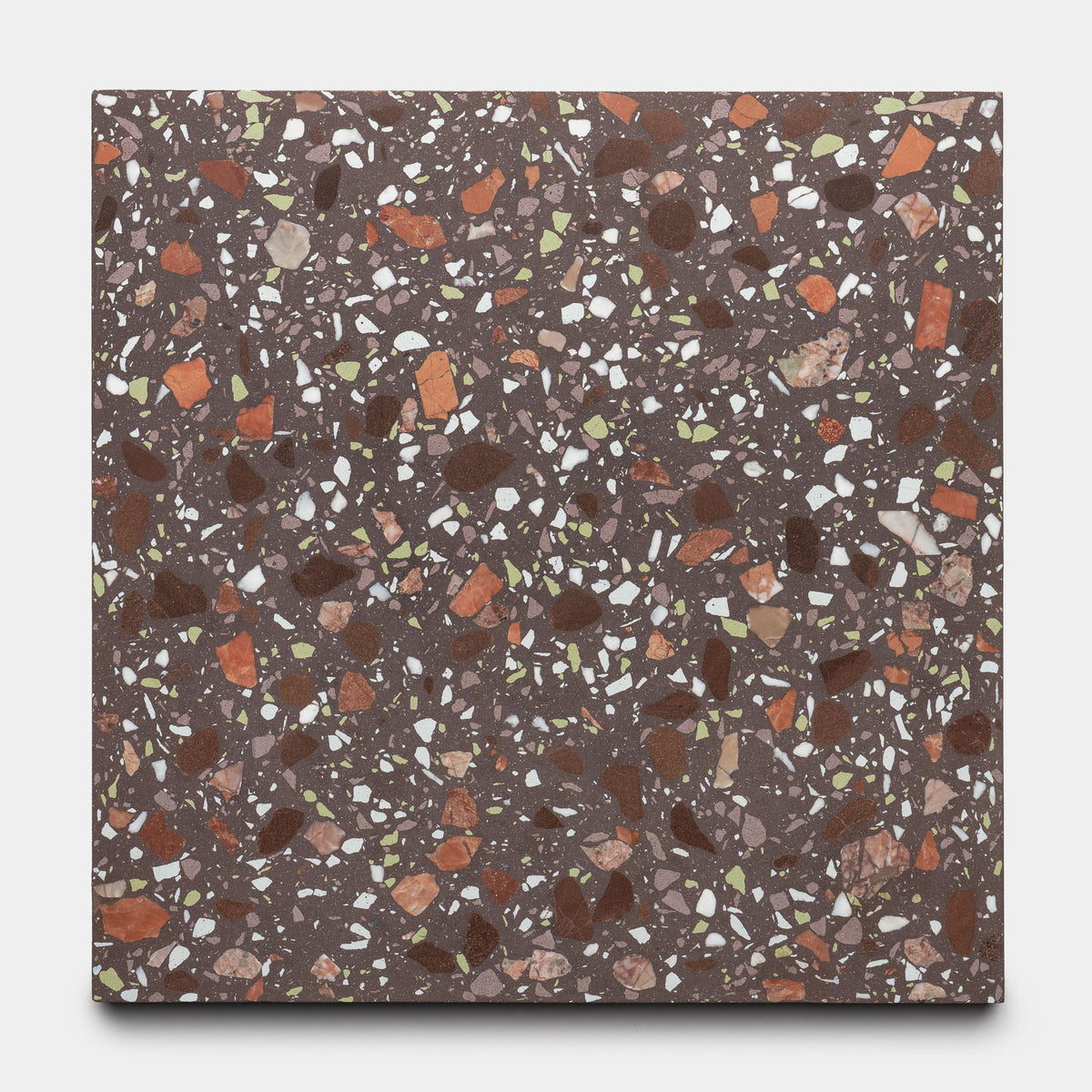 The Nocino 12x12 tile by Zia Tile features a dark brown base with white, red, orange, and green chips in varying sizes and shapes for a vibrant, speckled mosaic pattern.