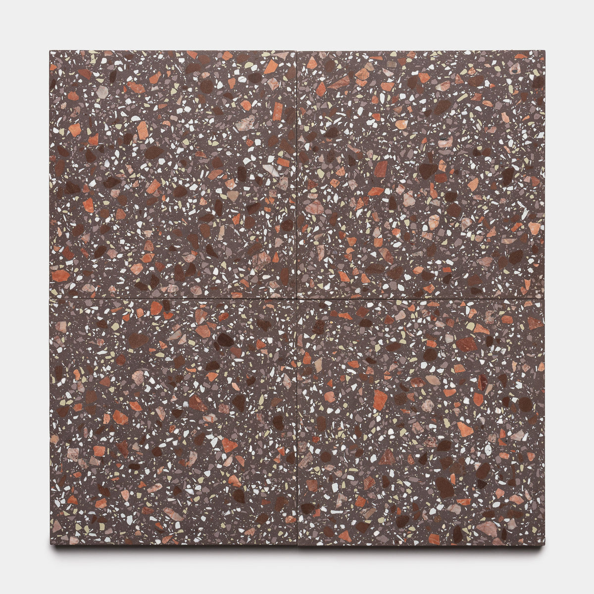 Four Nocino 12x12 tiles by Zia Tile are arranged in a square. Each brown terrazzo tile features red, white, and tan stone chips throughout the surface, displayed on a plain light background.