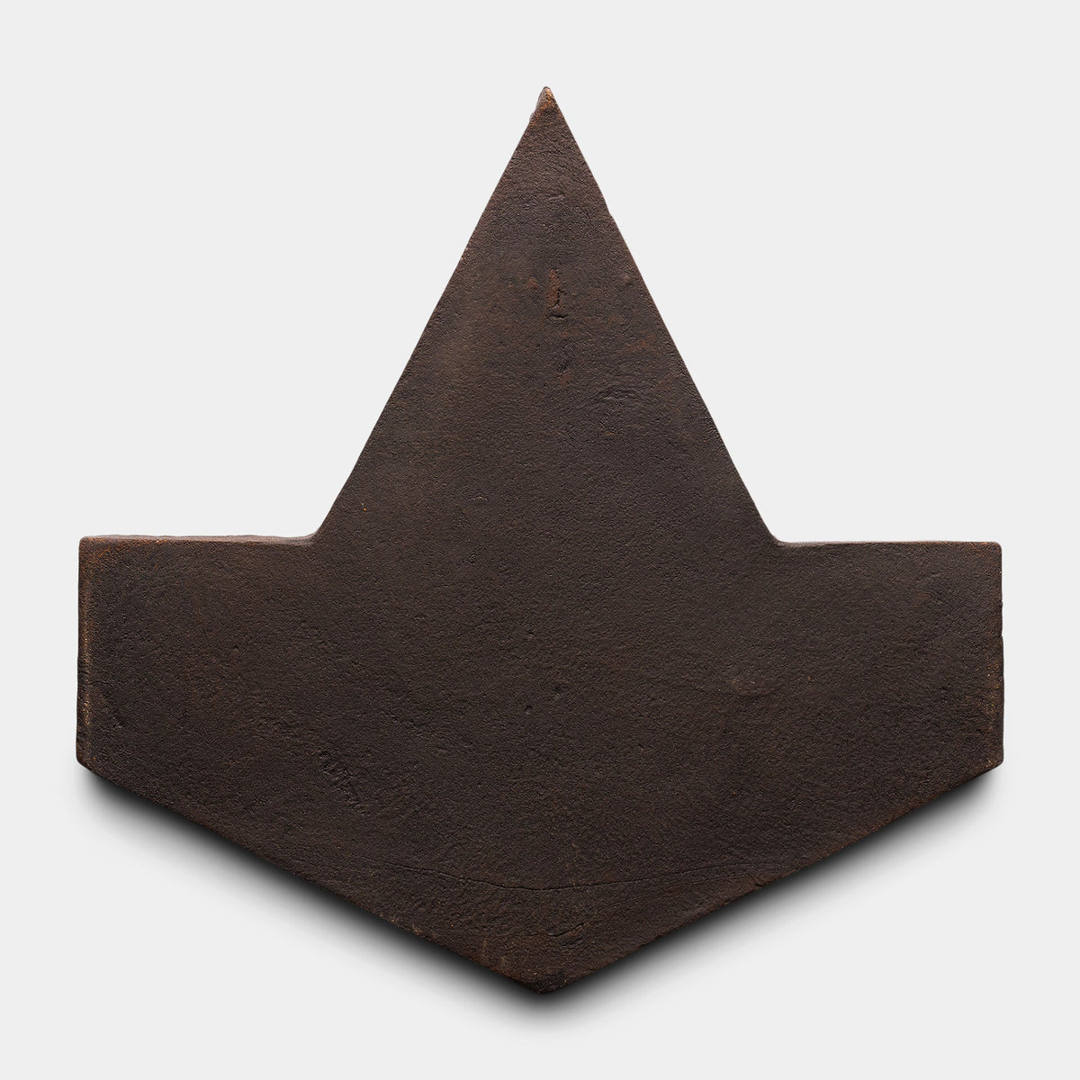 The Big Alcazar + Oscura sample by Zia Tile is a dark, rusted metal piece with a pointed triangular top and wide V-shaped base, resembling an abstract arrowhead, shown against a plain white background.