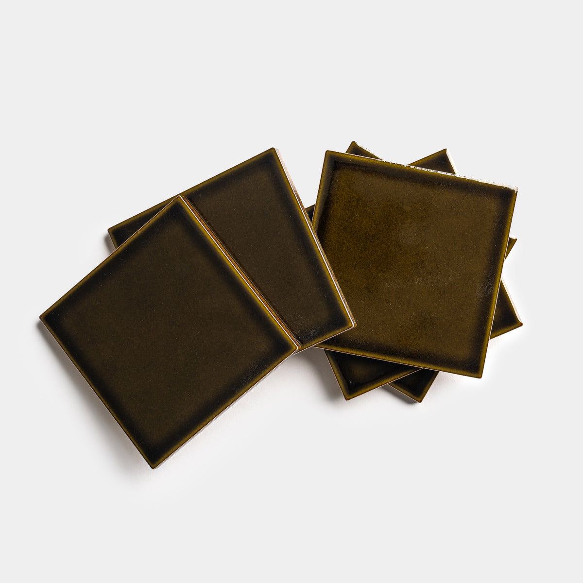 Four Oud 4x4 dark brown square ceramic coasters by Zia Tile, each with slightly raised edges, are stacked and slightly overlapped on a white background.